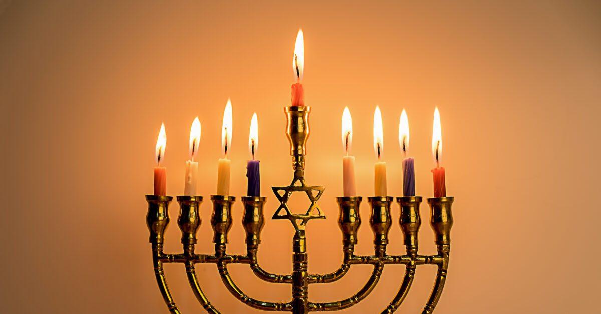 Hanukkah menorah with burning color candles for jewish holiday with wooden background.